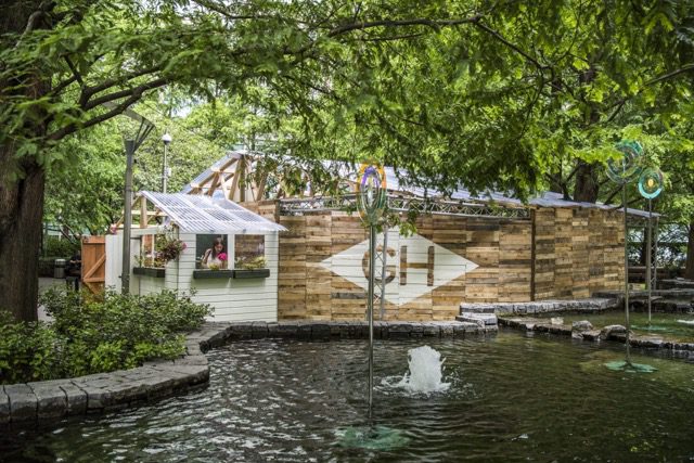 Binnenkant van een grote theaterzaal met rode stoelen en meerdere zitniveaus erboven. Het logo van het Nationaal Theater Praag in de linkerbovenhoek